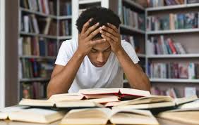 Stressed African student looking at smartphone, showing signs of digital overwhelm